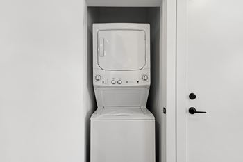 A white washing machine is sitting in a white door.